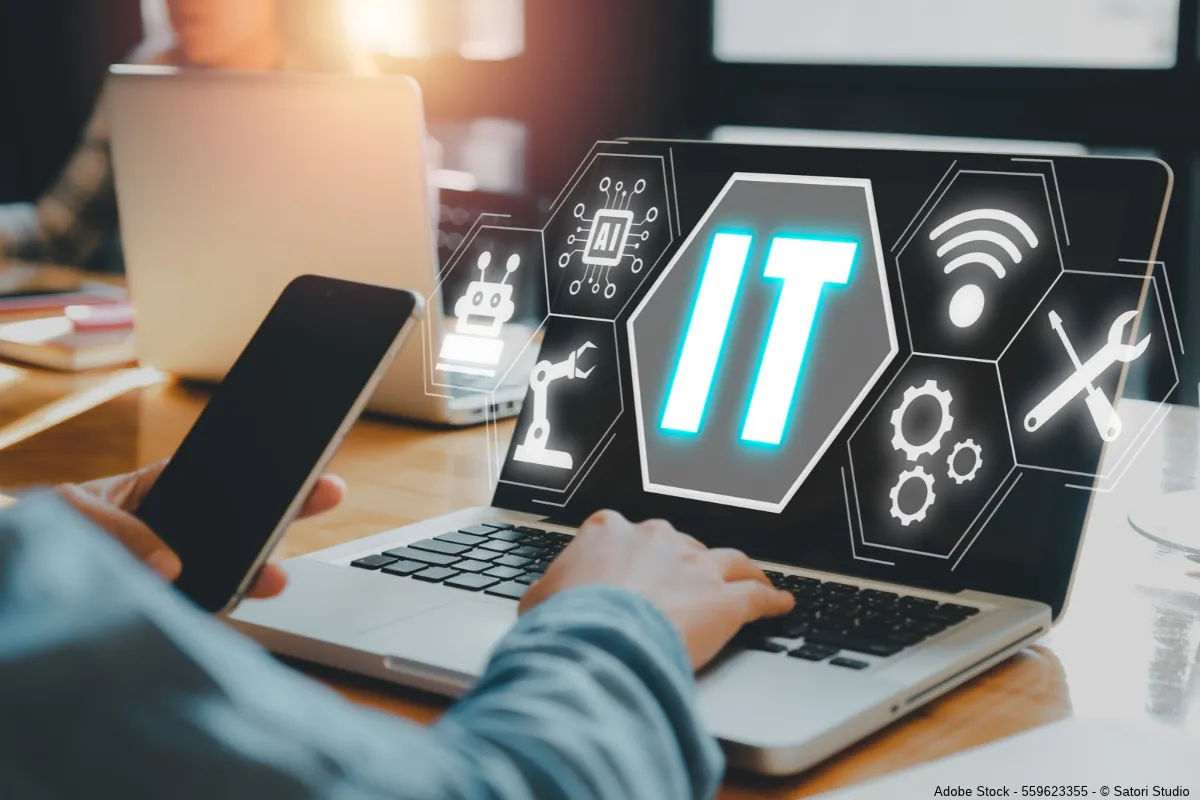 Eine Person arbeitet mit Smartphone und Laptop, während digitale Symbole für KI und Technik Berufe mit Zukunft in der IT veranschaulichen.
